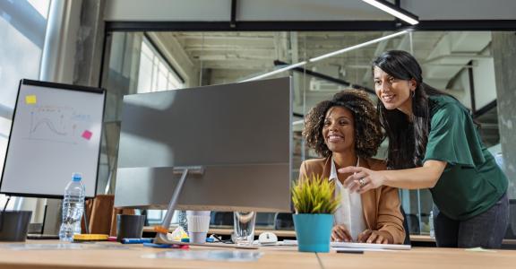 Two women working together at a computer.