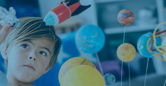 Young boy playing with rocket, astronaut and planet